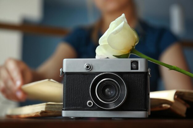 Vintage camera on table and blurred woman looking on photos