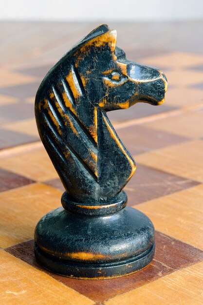 Vintage chess knight on empty wooden chessboard