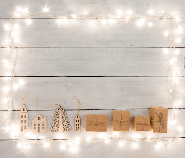 나무 테이블 선물 상자에 있는 빈티지 크리스마스 장식에는 트리 크리스마스 조명과 텍스트 복사 공간이 있습니다.