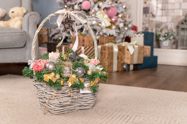Старинные рождественские подарки в волшебной композиции с корзиной. разноцветные шарики, сосновые шишки, сладкие конфеты, еловые ветки, грецкие орехи и снежинки. Стиль кантри. праздничное оформление. рождественские плетеные корзины