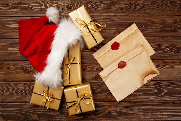 Фото Старинное рождественское поздравительное письмо и упакованные подарочные коробки на деревянном фоне