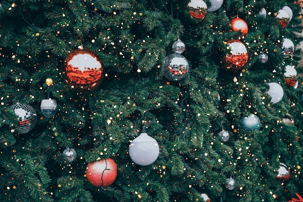 赤いボールの飾りと装飾、輝きの光とビンテージのクリスマスツリー。クリスマスと新年の休日の背景。ヴィンテージ色のトーン。