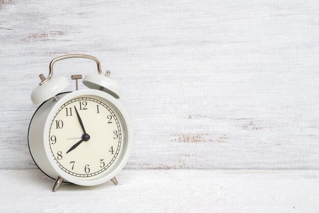 Vintage classic white alarm clock on white grunge background