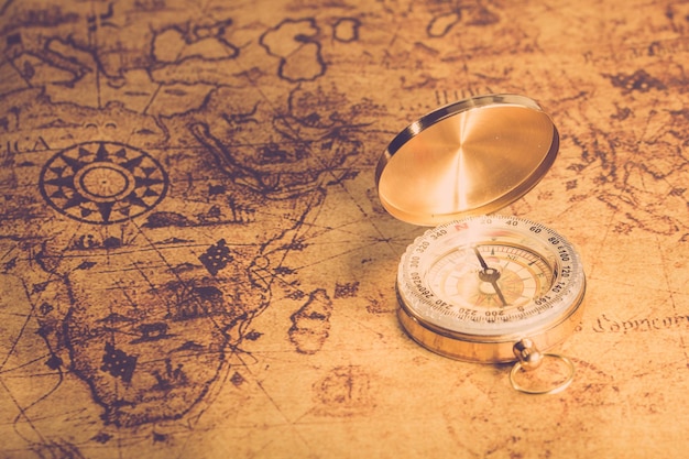 Винтажный компас на глобальной старой винтажной карте крупным планом