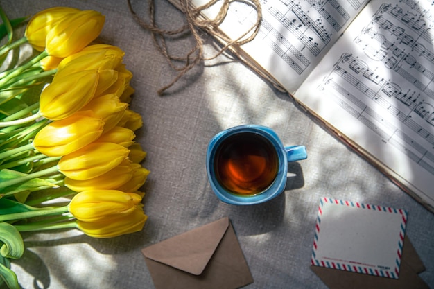 Vintage composition with a cup of tea tulips and notes flat lay