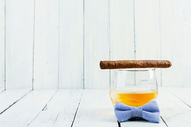 Vintage concept with view of whiskey and cigar on white wooden background