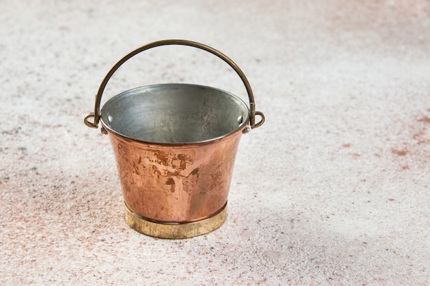 Vintage copper bucket on concrete background