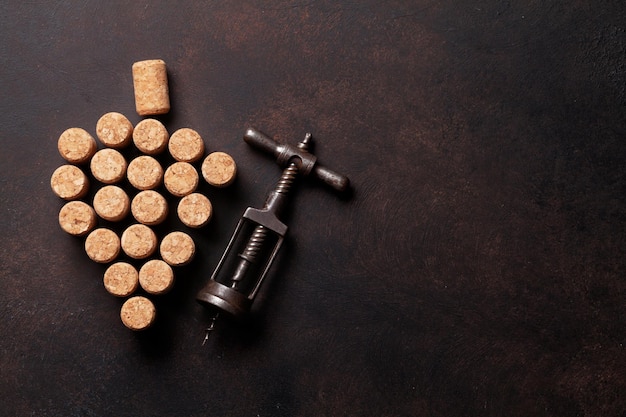 vintage corkscrew and wine corks on stone table top view with copy space