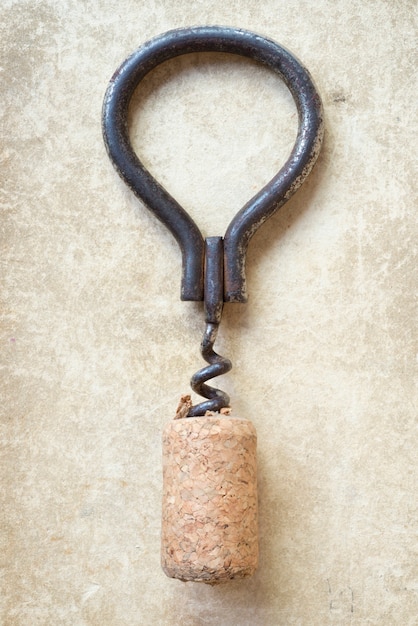 Vintage corkscrew with cork on old cardboard background