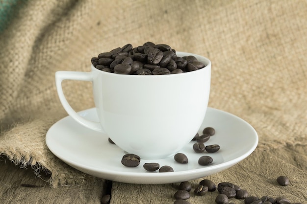 Vintage cup of  roasted coffee beans  on wooden background