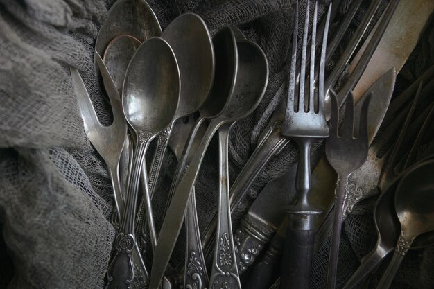 Vintage cutlery on dark fabric in a black wooden box, black background, top view