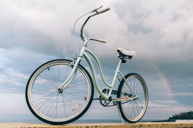 Vintage damesfiets op de achtergrond van de zee en een regenboog