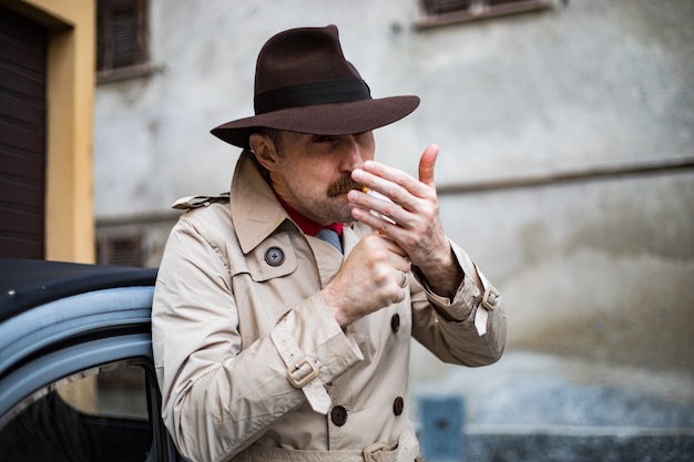 Photo vintage detective smoking a sigarette ina city slum