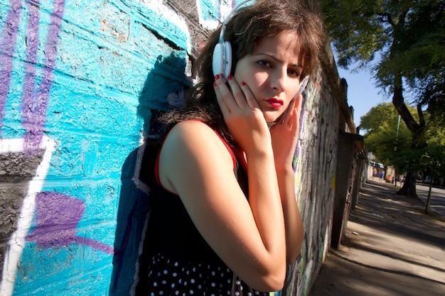 A vintage dressed girl listing to music in a urban environment.