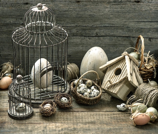 Vintage easter decoration with eggs, birdhouse and birdcage. nostalgic still life home interior. wooden background