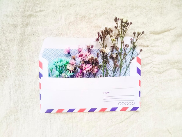 Photo a vintage envelope with small little cute flowers. gift box greeting card for valentines on white linen background