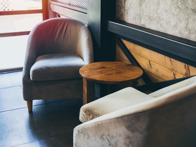 Vintage fabric armchair with round wooden table near the wall concrete black steel and wooden wall