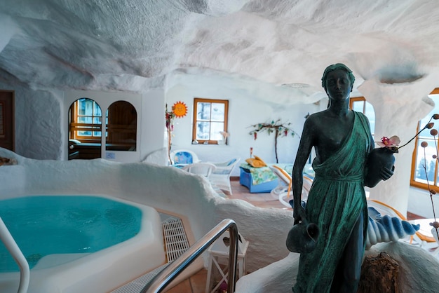 Vintage female statue displayed by jacuzzi under white roof in hotel