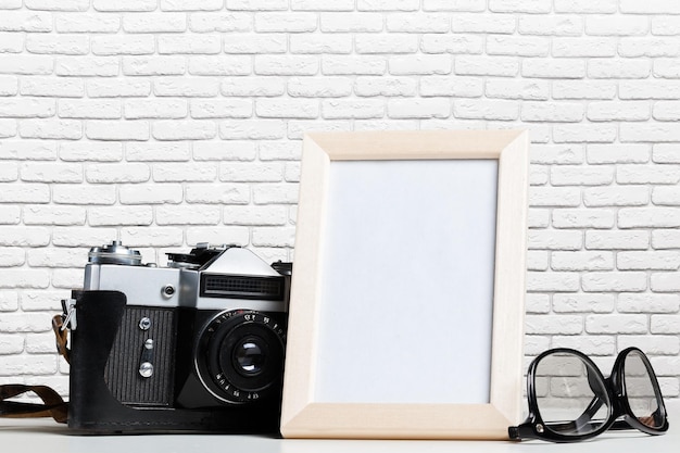 Vintage film camera and blank photo frame on wooden table