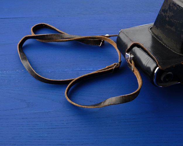 Винтаж пленочной камеры в кожаном футляре на деревянном синем