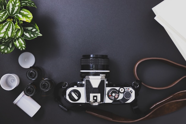 Vintage film cameras and film rolls, books, trees placed on a black background 