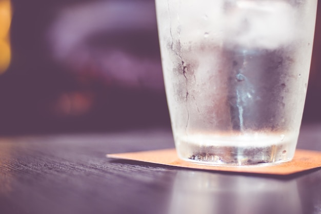 Винтажный фильтр: Холодный стакан воды на деревянном столе в ресторане