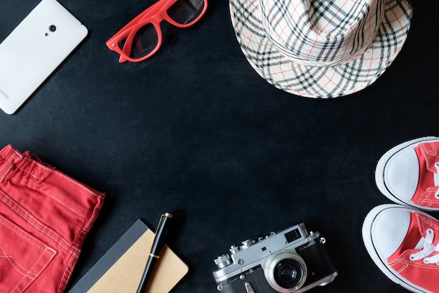 Vintage fineart film photography set of red sneakers, red glasses, red jeans, vintage camera, white phone, notebook, stylus pen, checkered hat