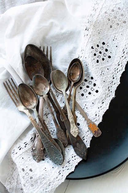 Vintage forks and spoons on black plate with white tablecloth