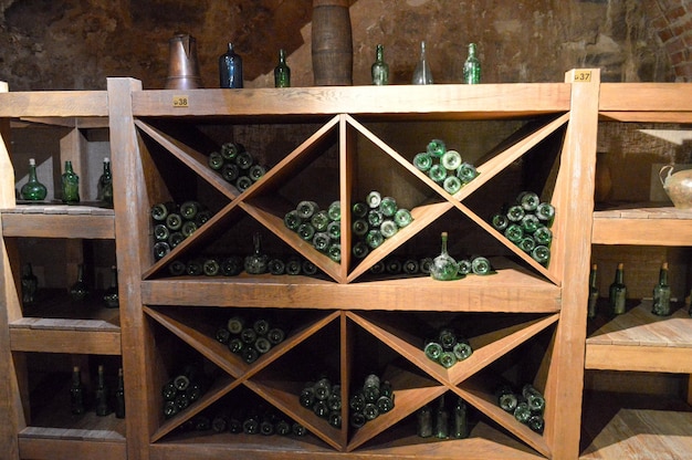 Vintage green empty wine and beer glass bottles in a wine cupboard with shelves