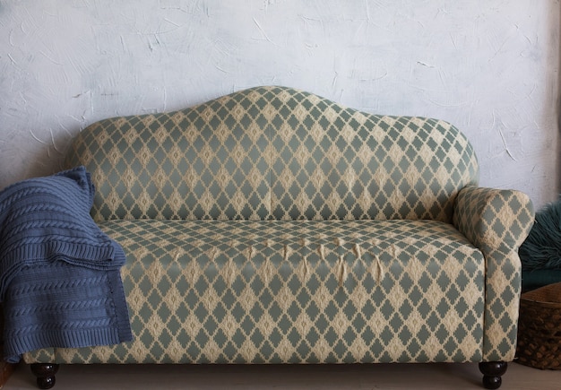 Vintage grey couch with a knitted blanket in a light room