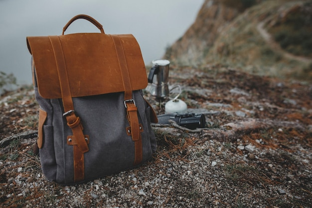 Vintage hipster backpack by tree on river bank in fog