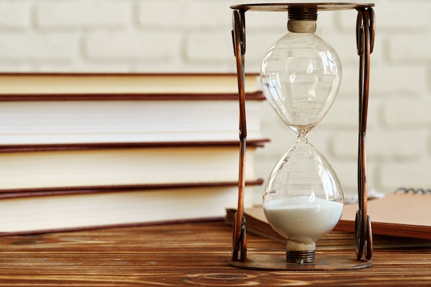 Photo vintage hourglass against a stack of old books close up
