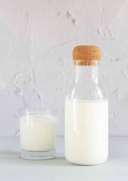 Photo vintage jar of homemade yogurt, kefir, fermented milk or sour cream next to drinking glass on kitchen table. vertical photo