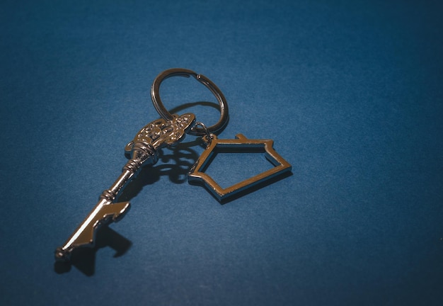 Photo vintage key and house shape keychain on blue backgroundreal estate properties investment concept