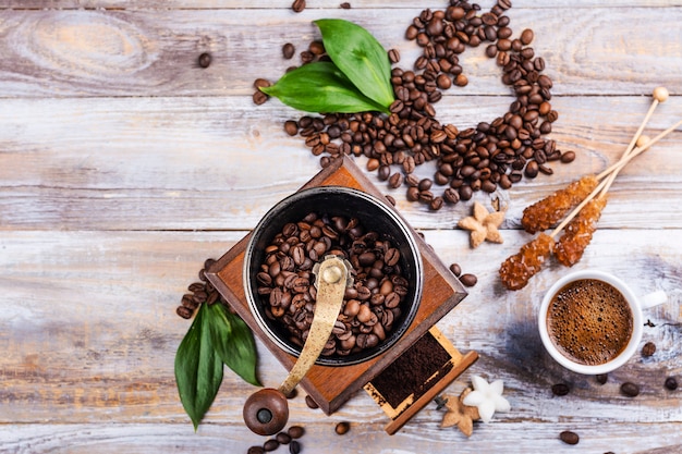 Vintage koffiemolen, bonen en kopje koffie op houten tafel