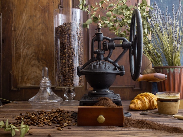 vintage koffiemolen koffie en croissant op een donkere achtergrond
