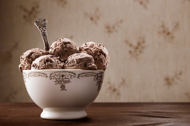 Vintage kom en lepel met veel chocoladeroomijsballen. Heerlijk huisgemaakt ijsdessert op een rustieke houten tafel met een vintage achtergrond.