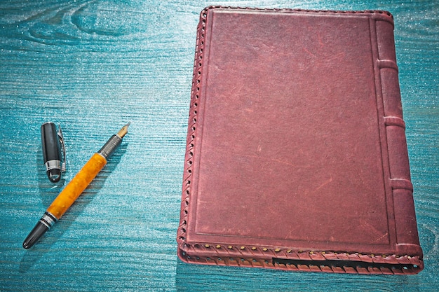 Vintage leather notepad and fountain pen on blue painted board