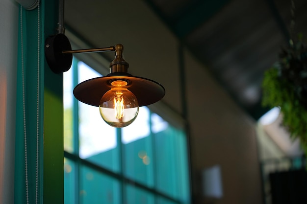 갈색 및 주황색 톤의 고대 블록 벽이 있는 레스토랑 또는 카페의 빈티지 LED 에디슨 램프 또는 백열 전구