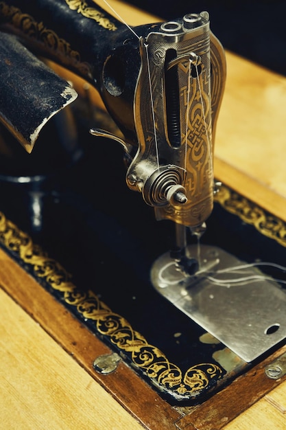 Vintage manual sewing machine at wooden table in room closeup