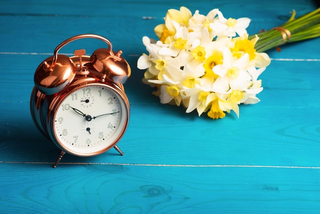 Vintage mechanische wekker met gele narcissen op een blauwe houten achtergrond modekleuren ondersteuning voor oekraïne kleuren van de oekraïense vlag goedemorgen, we komen uit oekraïne