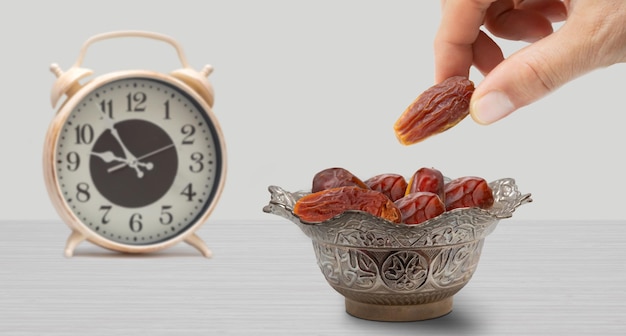 Vintage metal bowl full of pitted date fruits on wooden table.
traditional iftar food. symbolizing