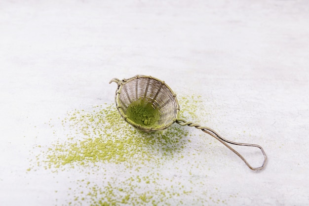 Vintage metal strainer with Matcha tea. Top View