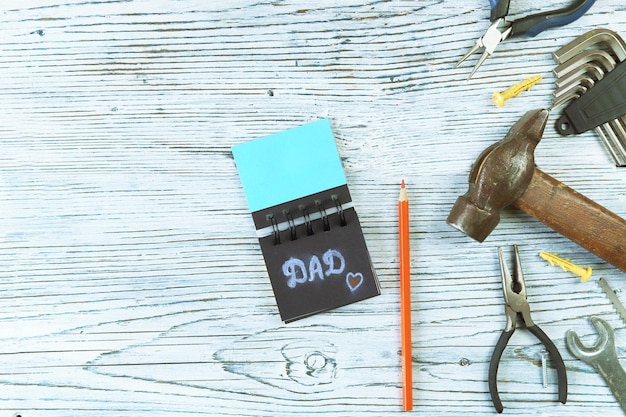 Vintage metal tools the inscription dad in a notebook and a pencil the concept of Father's Day