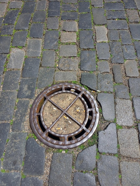 Foto vintage metalen luik op een riool of waterkraan voor regenwaterafvoer op een straatsteenachtergrond