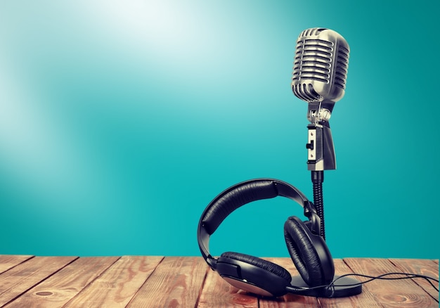 Vintage microphone and modern headphones on blue background