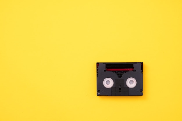 Photo vintage mini dv cassette tape used for recording video back in a day. plastic, magnetic, analog film tape on yellow background