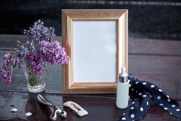 Vintage mock-up frame met lila bloemen serum druppelfles gezichtsmassager haarstrik en haarspeld