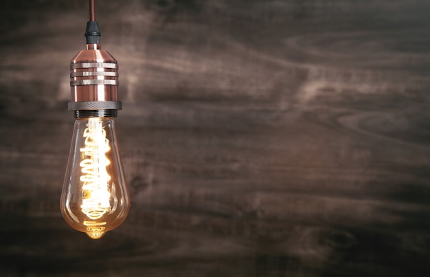 Vintage modern light bulb over wooden background.