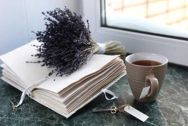 Vintage notebook on green marble windowsill opened with blank pages and a bunch of lavender